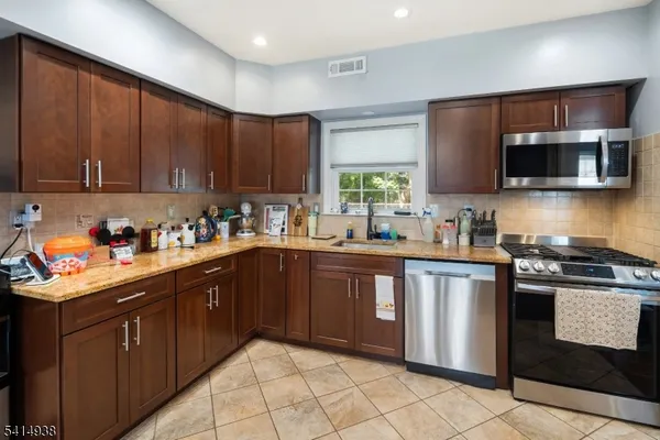 a kitchen with stainless steel appliances granite countertop wooden cabinets a stove top oven a sink and dishwasher