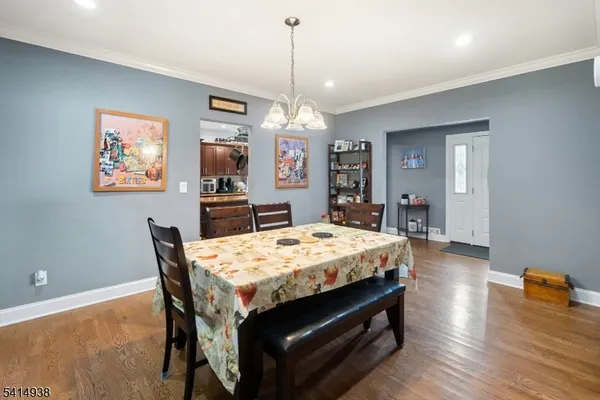 a dining hall with stainless steel appliances granite countertop a dining table chairs with wooden floor and chandelier