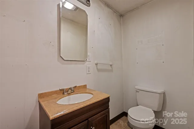 a bathroom with a granite countertop toilet a sink and mirror