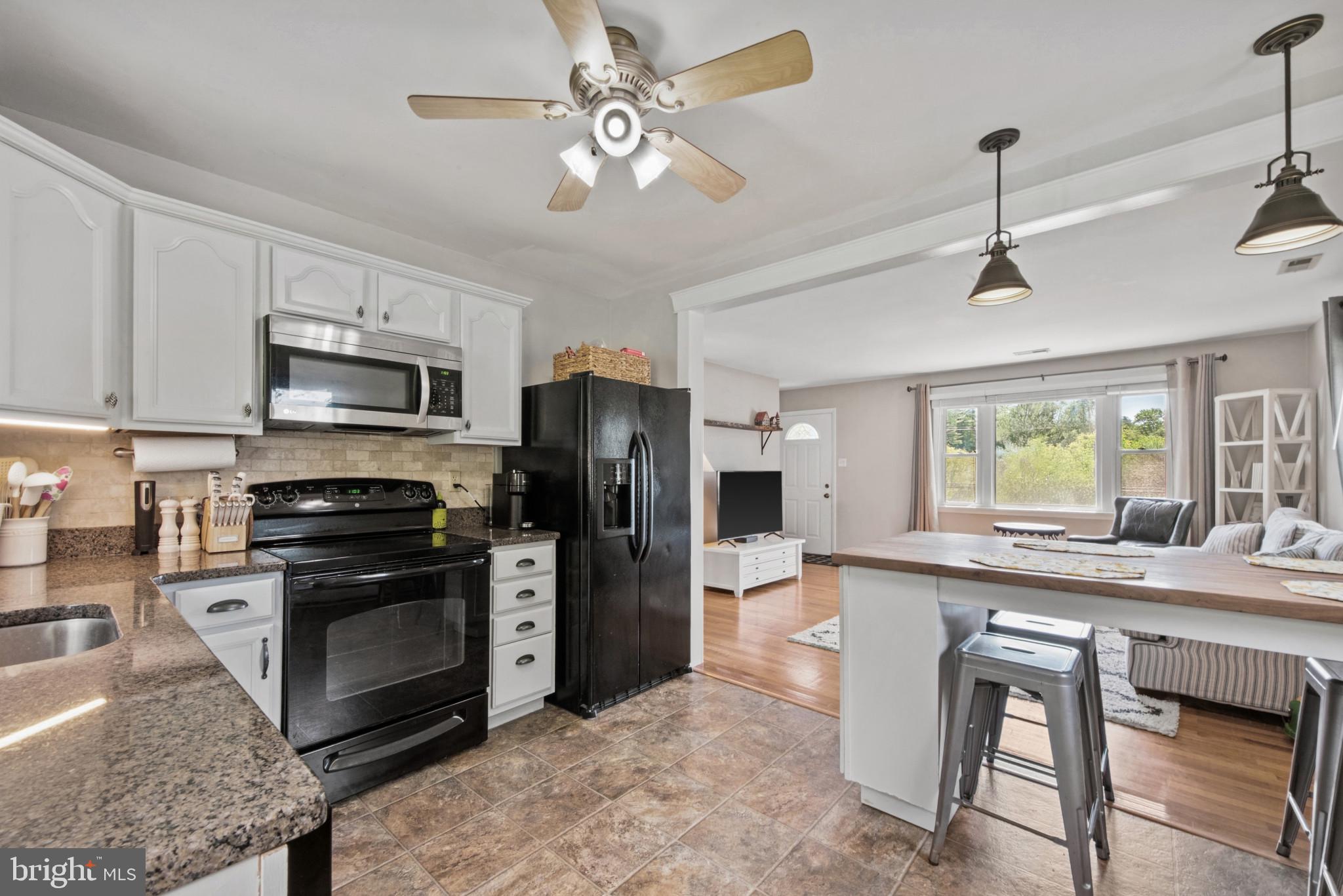 3242 Lineboro Road Manchester, MD 21102 - Photo 11 of 30 a kitchen with stainless steel appliances granite countertop a stove a refrigerator a oven a sink with a dining table and chairs