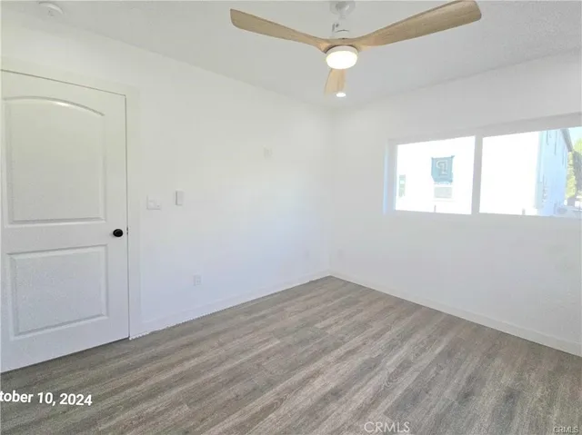 an empty room with wooden floor fan and windows