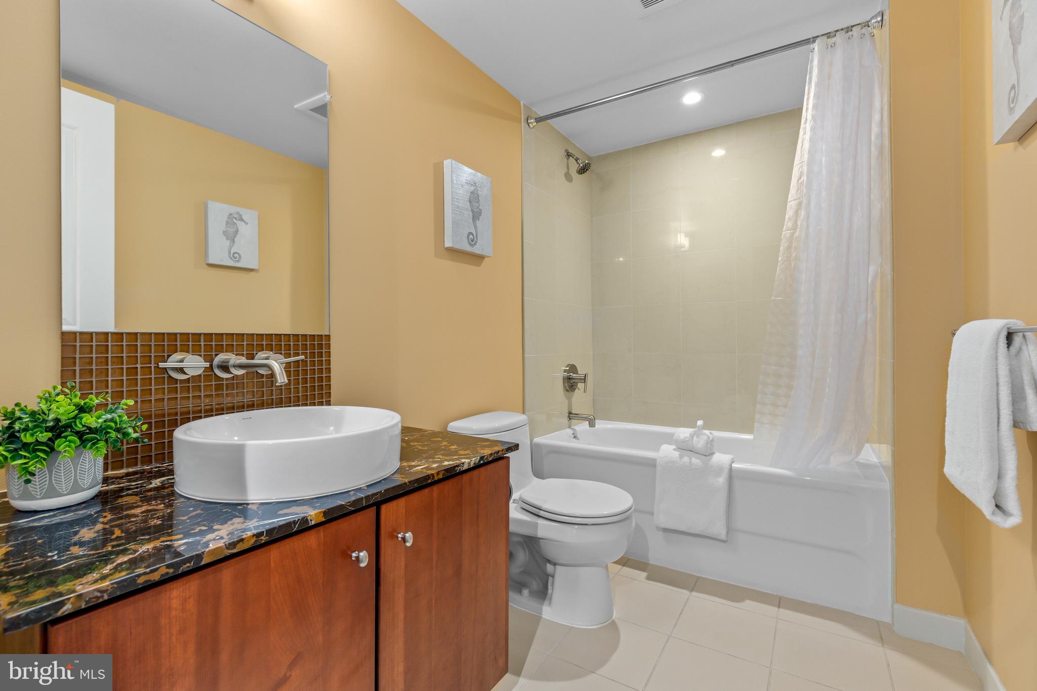 1025 First Street Southeast, Unit 611 Washington, DC 20003 - Photo 6 of 32 a bathroom with a granite countertop sink a toilet a mirror and shower