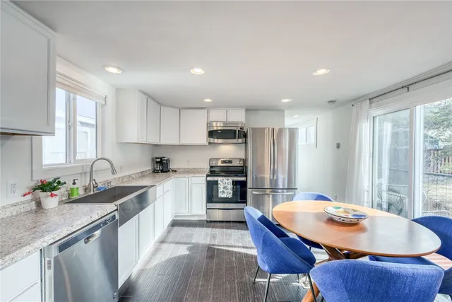 a kitchen with stainless steel appliances granite countertop a sink a stove a refrigerator cabinets and a dining table