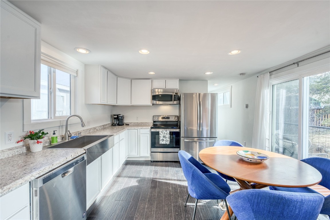 a kitchen with stainless steel appliances granite countertop a sink a stove a refrigerator cabinets and a dining table