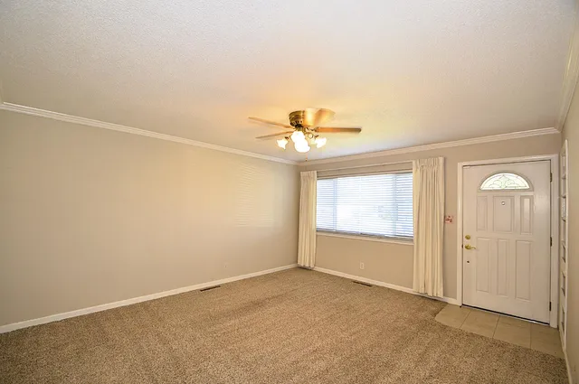 an empty room with a ceiling fan and windows