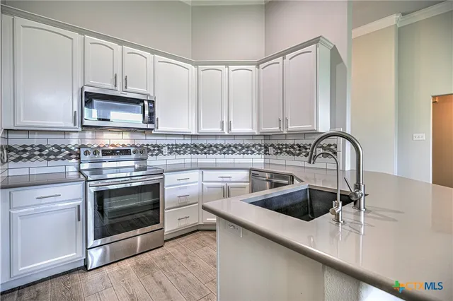 a kitchen with granite countertop a sink stainless steel appliances and cabinets