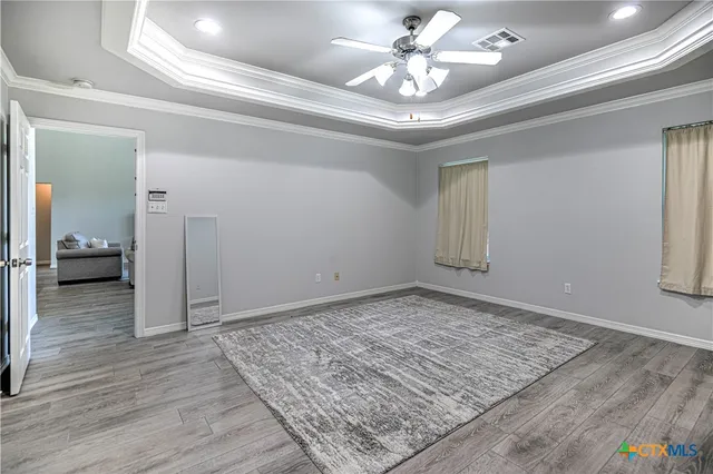 an empty room with wooden floor chandelier fan and windows