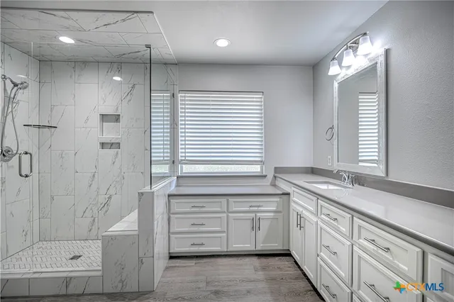 a bathroom with a granite countertop sink a large mirror and a bathtub