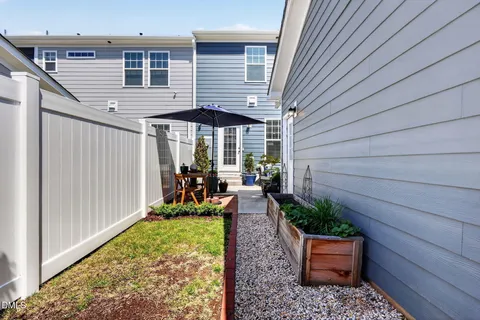 a view of a backyard with chairs and floor to ceiling window and wooden fence