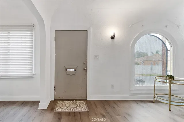 a view of an empty room with window and wooden floor