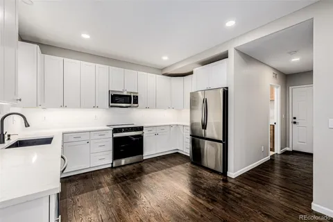 an empty room with chandelier fan and windows
