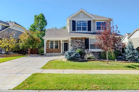 a front view of a house with a garden and trees