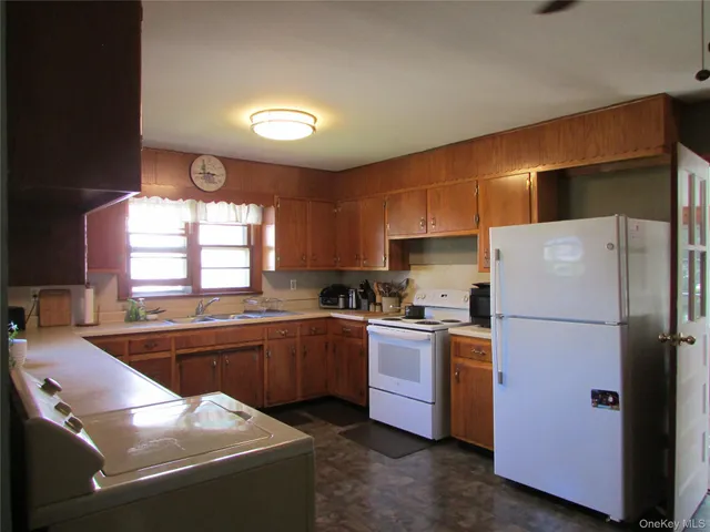 a kitchen with stainless steel appliances granite countertop a refrigerator sink stove dining table and chairs