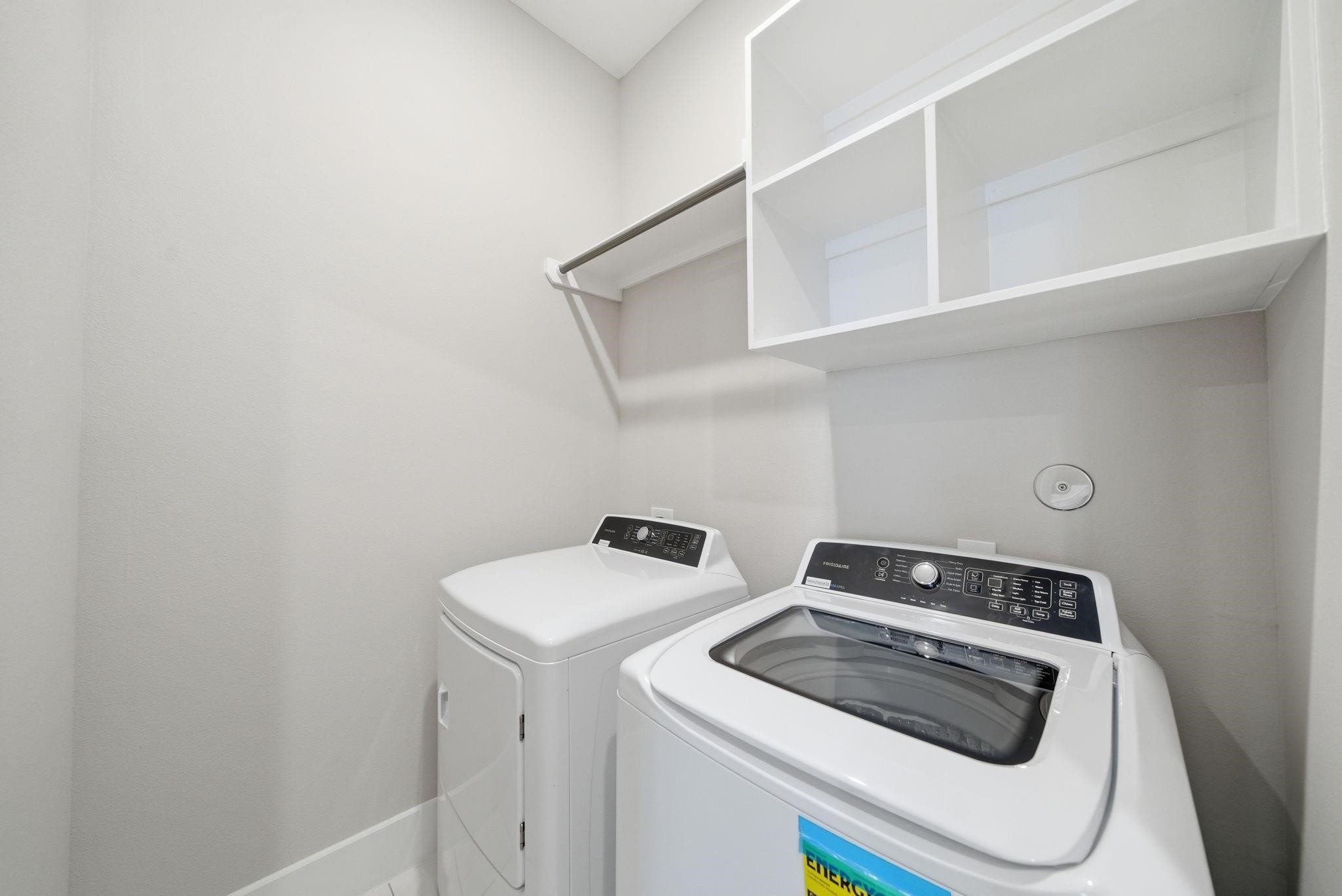 4013 Griggs Road, Unit F Houston, TX 77021 - Photo 5 of 35 Modern laundry room featuring a sleek washer and dryer set, ample shelving, and a convenient hanging rod for easy organization.