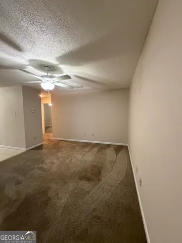 an empty room with windows and ceiling fan