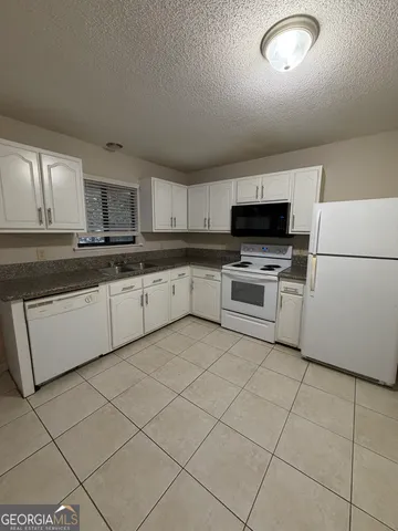 a view of a refrigerator in kitchen and an empty room