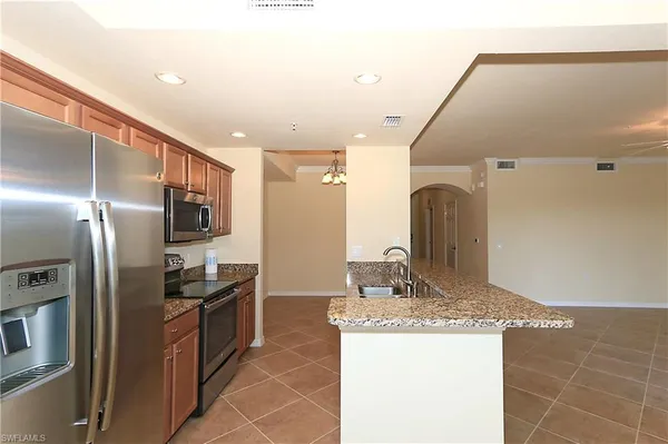 a kitchen with stainless steel appliances kitchen island granite countertop a refrigerator and a sink