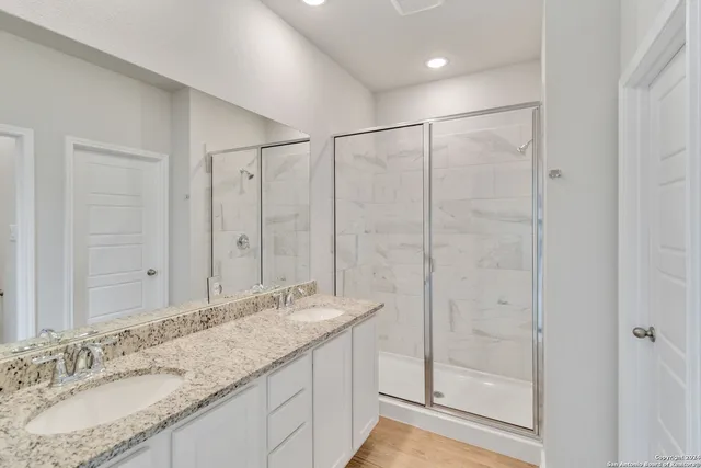 a bathroom with a granite countertop sink a mirror and shower