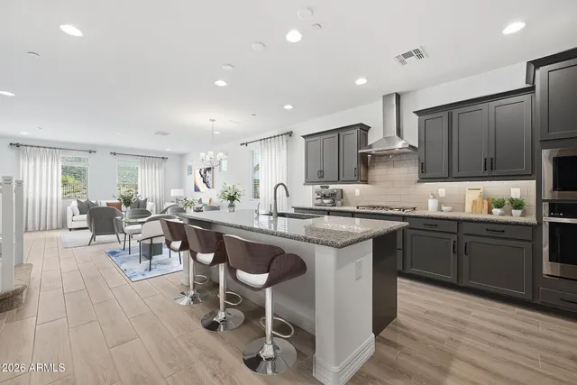 a kitchen with stainless steel appliances granite countertop a table chairs sink refrigerator and cabinets