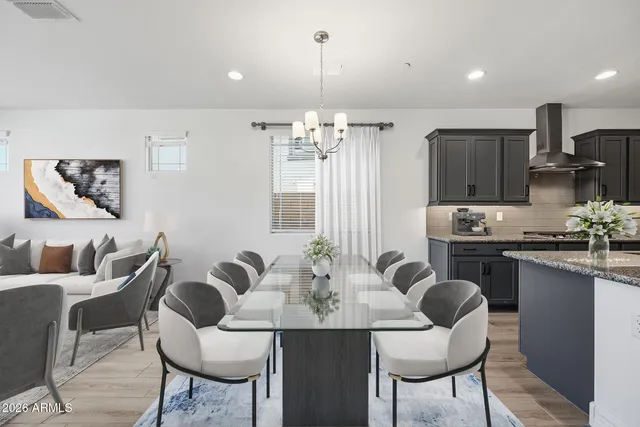 a kitchen with stainless steel appliances kitchen island granite countertop a dining table chairs and a refrigerator