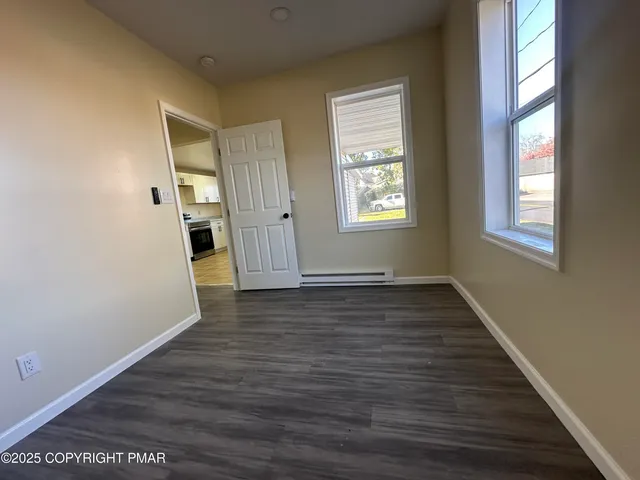 a view of an empty room with wooden floor and a window