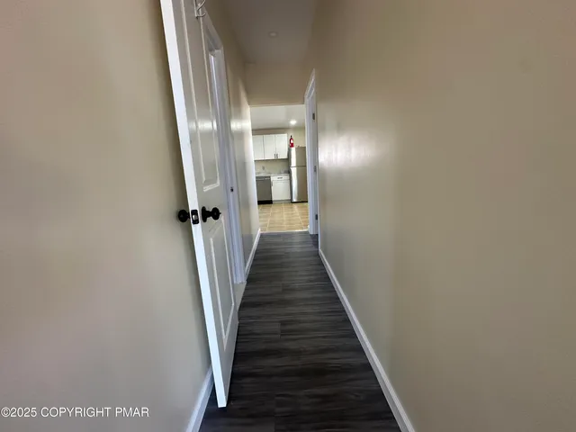 a view of an empty room with a window and wooden floor