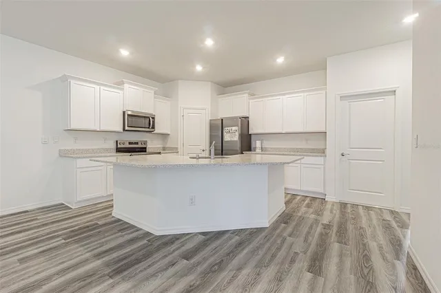 a view of a kitchen with white cabinets and wooden floor