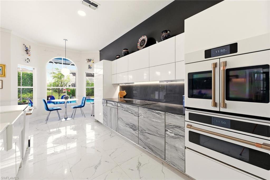 209 Countryside Drive Naples, FL 34104 - Photo 11 of 50 Kitchen featuring dark countertops, modern cabinets, pendant lighting, white double oven, and light marble finish flooring