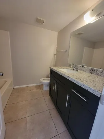 a bathroom with a granite countertop sink a toilet and a mirror