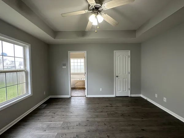an empty room with wooden floor fan and windows