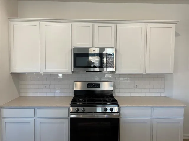 a kitchen with stainless steel appliances granite countertop white cabinets and a stove a oven with white countertops