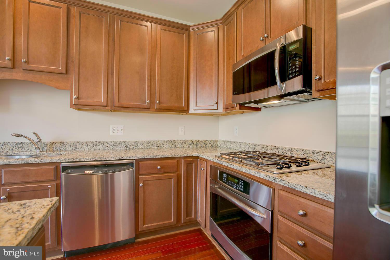 141 Short Branch Road Stafford, VA 22556 - Photo 13 of 30 a kitchen with stainless steel appliances granite countertop a stove a microwave and wooden cabinets