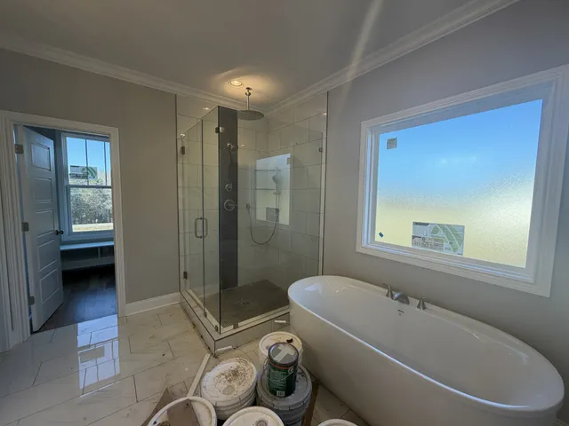 a bathroom with a tub toilet shower and window