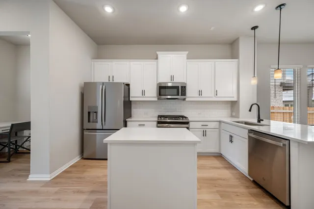 a kitchen with stainless steel appliances a sink stove refrigerator and cabinets