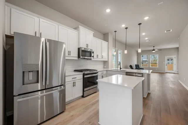 a kitchen with stainless steel appliances granite countertop a refrigerator a stove a sink and a microwave