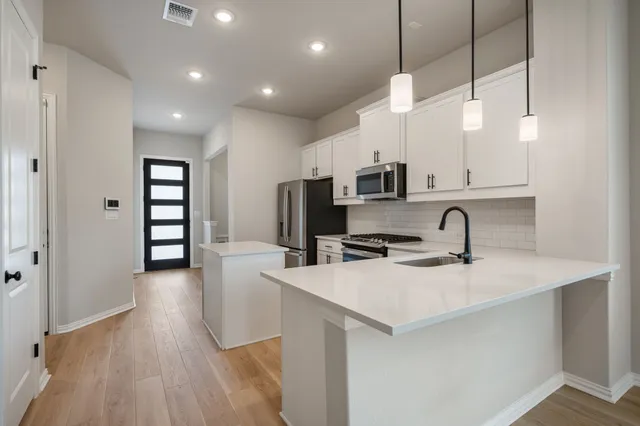 a kitchen with stainless steel appliances granite countertop a sink a stove and a wooden floors