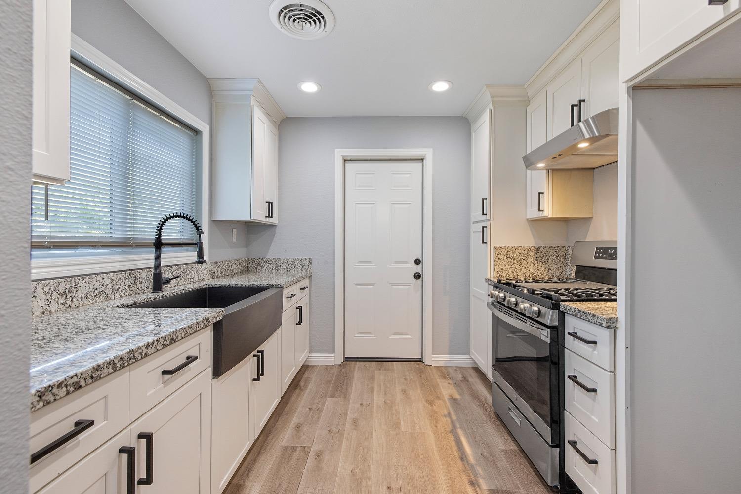 71 East Griffith Way Fresno, CA 93704 - Photo 13 of 35 a kitchen with granite countertop a sink stove and cabinets