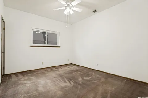 an empty room with a fan & a window