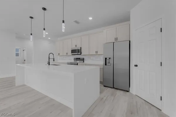 a view of a kitchen with refrigerator and white cabinets