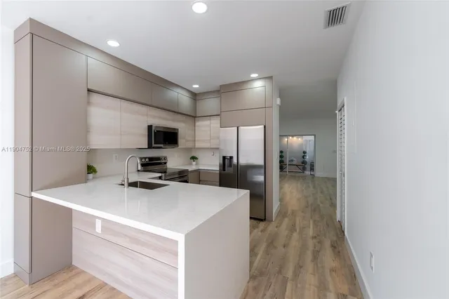 a kitchen with a sink a counter top space stainless steel appliances and cabinets