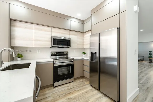 a kitchen with stainless steel appliances granite countertop a refrigerator a sink a stove top oven and a refrigerator