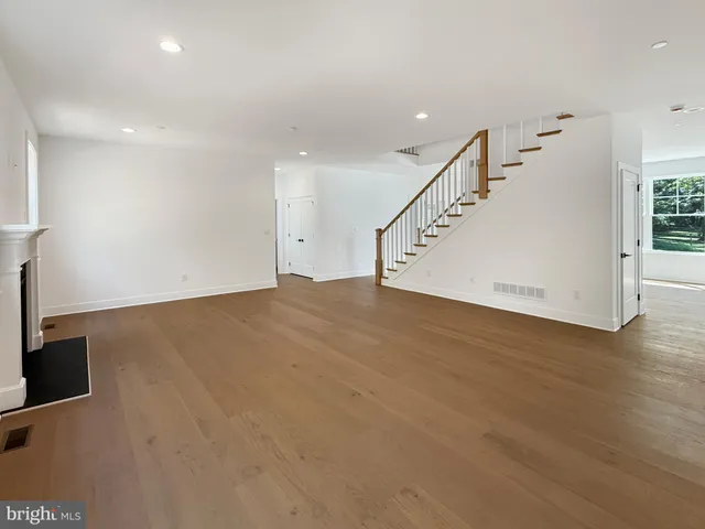 a view of an empty room with wooden floor and stairs