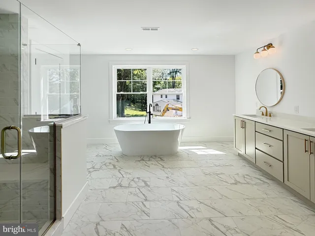 a spacious bathroom with a granite countertop sink a mirror and a bathtub