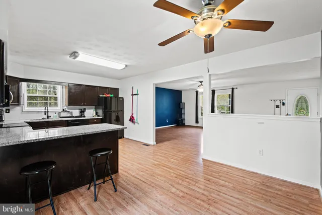 a kitchen with stainless steel appliances kitchen island granite countertop a sink a stove a dining table and chairs with wooden floor