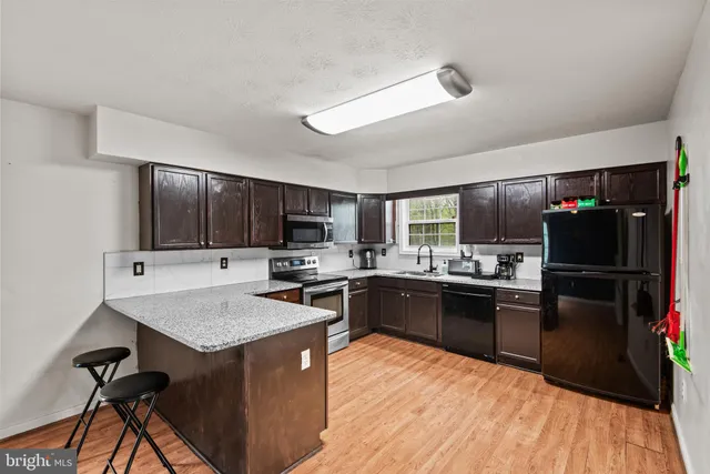 a kitchen with kitchen island granite countertop stainless steel appliances and wooden cabinets