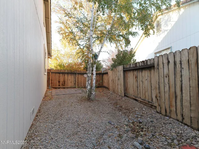 a view of a backyard with wooden fence and a large tree