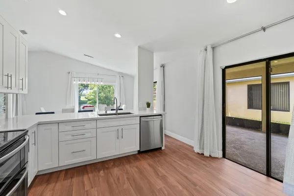 a kitchen with stainless steel appliances granite countertop a stove a sink and a refrigerator with wooden floors