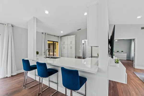 a large kitchen with cabinets a sink and chairs