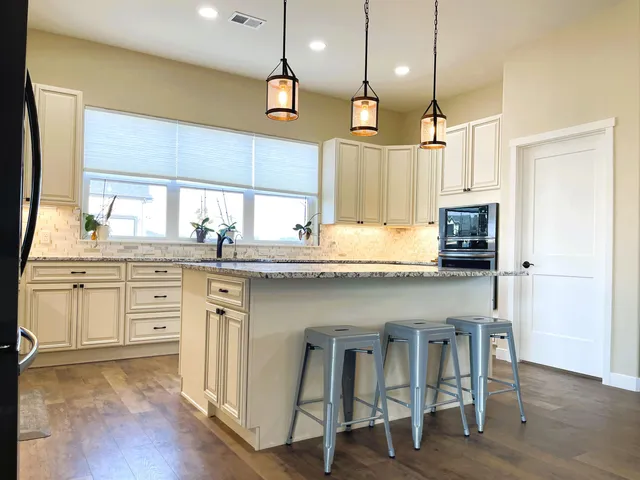 a kitchen with stainless steel appliances kitchen island granite countertop a sink a stove and a refrigerator