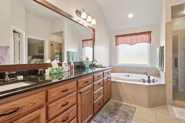 a spacious bathroom with a tub sink shower and mirror